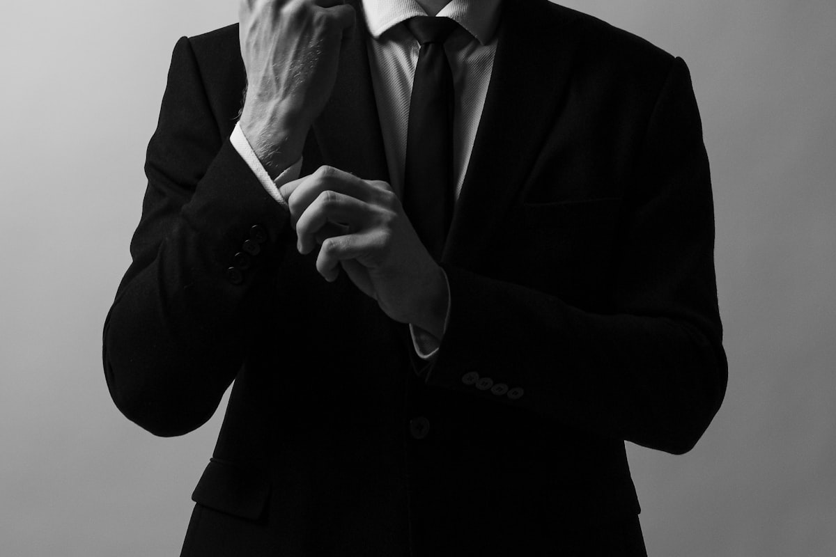 Man in a dark suit adjusting his necktie