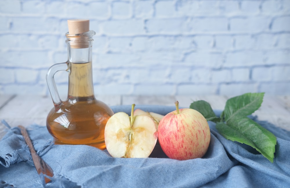 Bottle of apple cider vinegar next to a cut apple